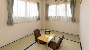 A room with tatami flooring, a wooden table, two chairs, and two windows with curtains. - Tabist Business Ryokan Duck Ishinomaki Hebita (Isinomaki)