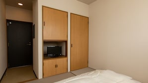 Een hotelkamer met een bed, een televisie op een plank en een kledingkast.
