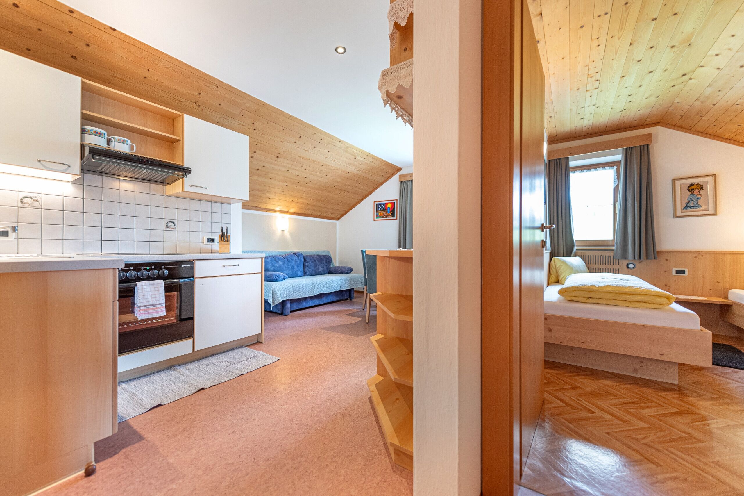 Eine kompakte Küche mit Holzschränken, einem eingebauten Ofen und einem Essbereich mit Tisch und Stühlen.