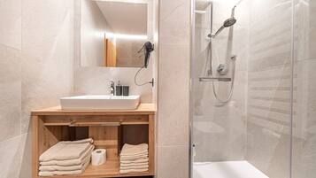 A modern bathroom with a wooden vanity, a sink, and a glass-enclosed shower.