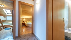 A modern hotel room with a loft bed, a small seating area, and a bathroom with a bathtub. - Holiday Farm Al Cir 400B (San Martino in Badia)