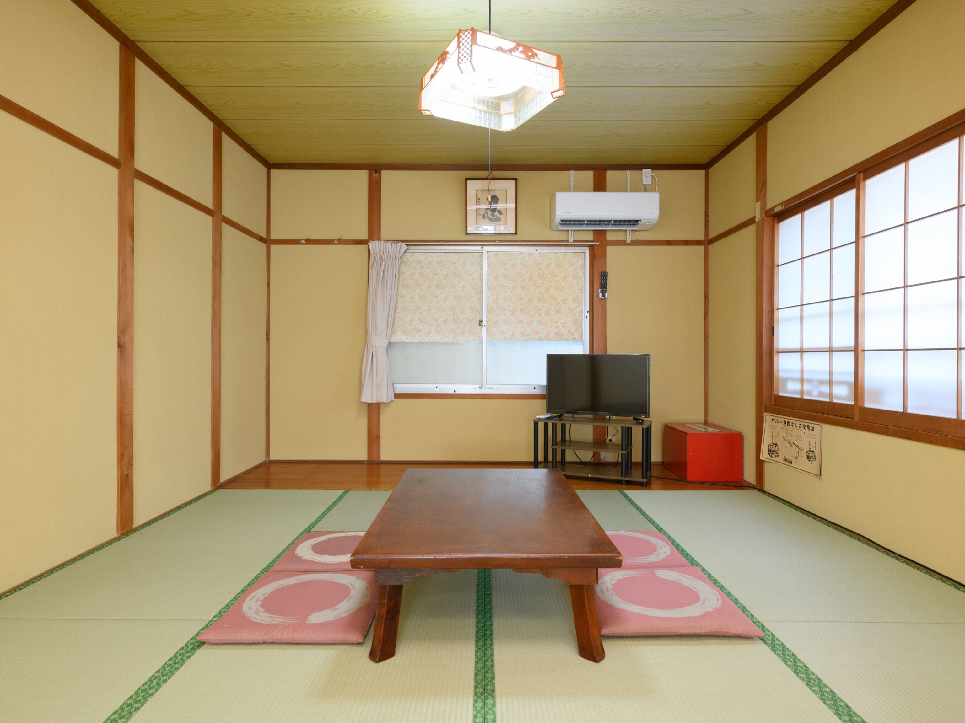 Een traditionele Japanse kamer met tatami vloeren, een lage tafel, een televisie en een schuifdeur.