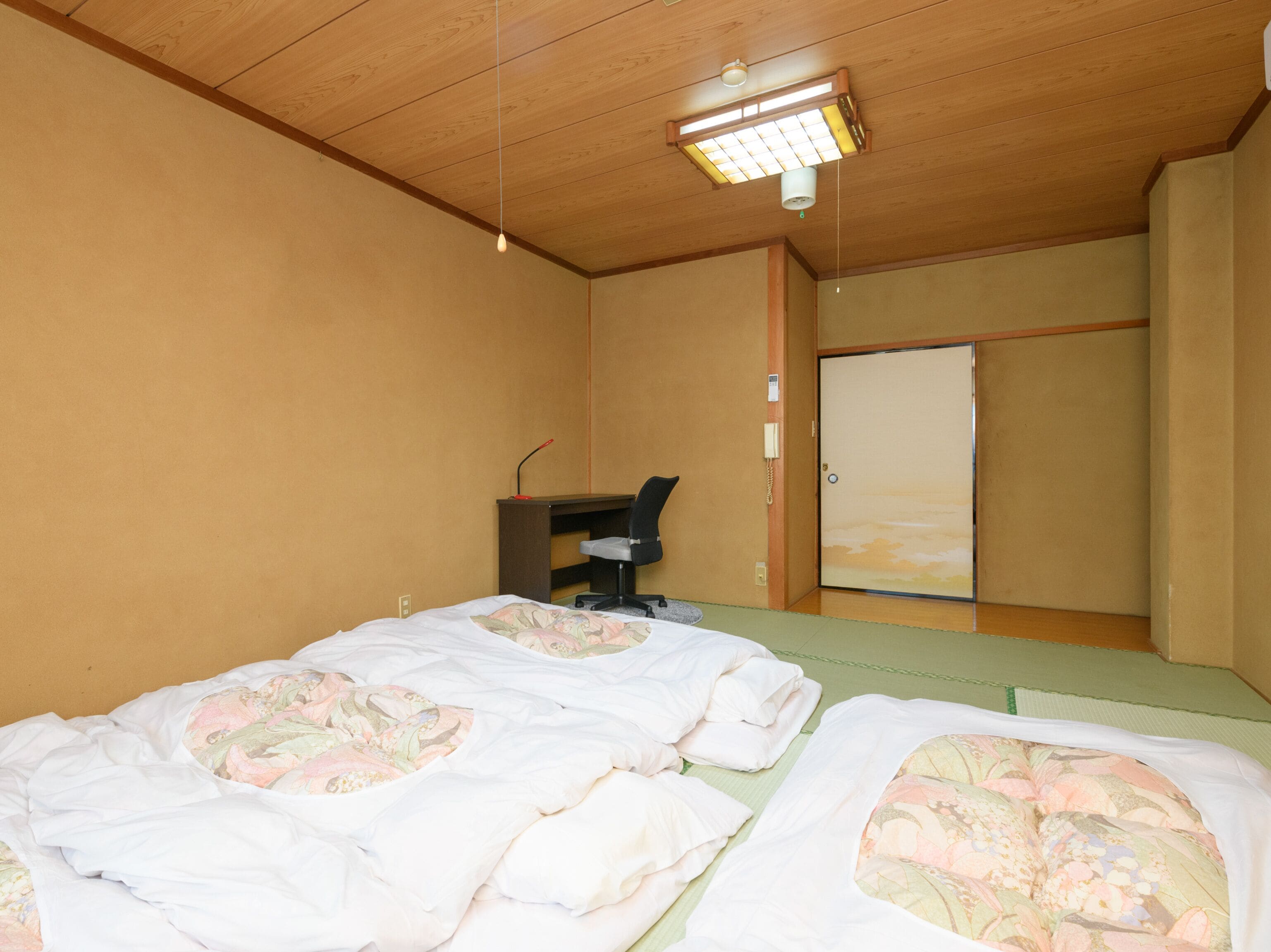 A room with two beds, a desk, a chair, and a wardrobe.