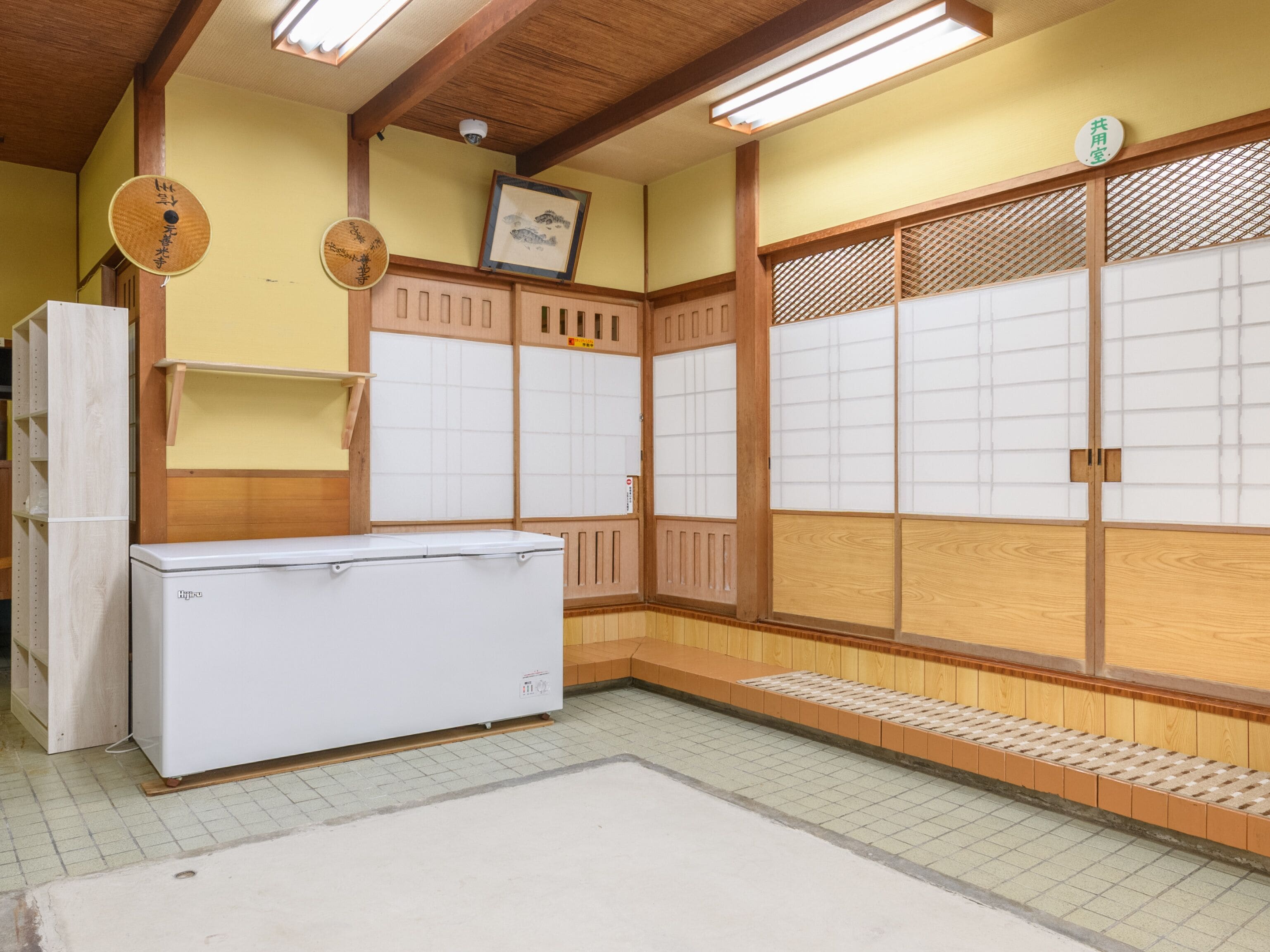 A traditional Japanese room with tatami flooring, a refrigerator, sliding doors, and a ceiling fan.