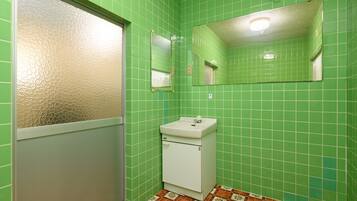 A bathroom with green tiled walls, a white sink, a mirror, and a patterned floor.
