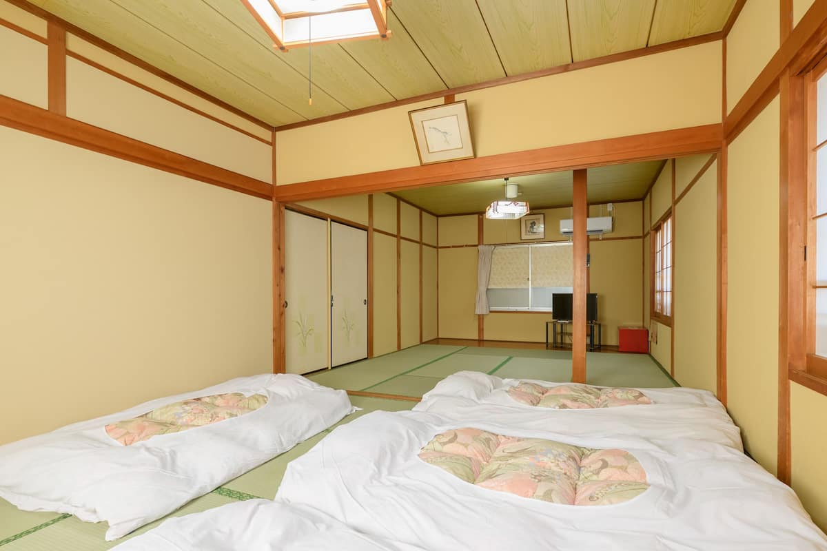 Une pièce de style japonais traditionnel, avec un sol recouvert de tatamis, deux nattes de tatami, un plafond en bois et une porte coulissante ornée de motifs floraux.