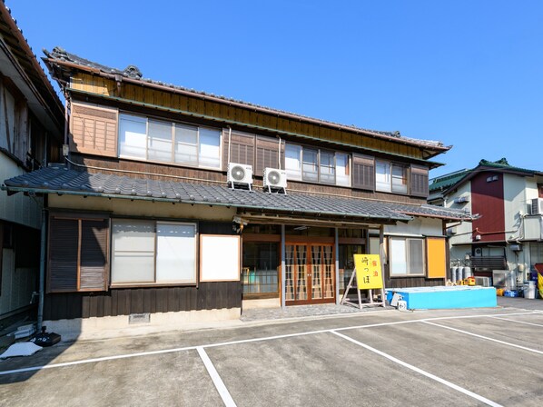 Un edificio japonés tradicional con fachada de madera, ventanas amplias y tejado de tejas.
