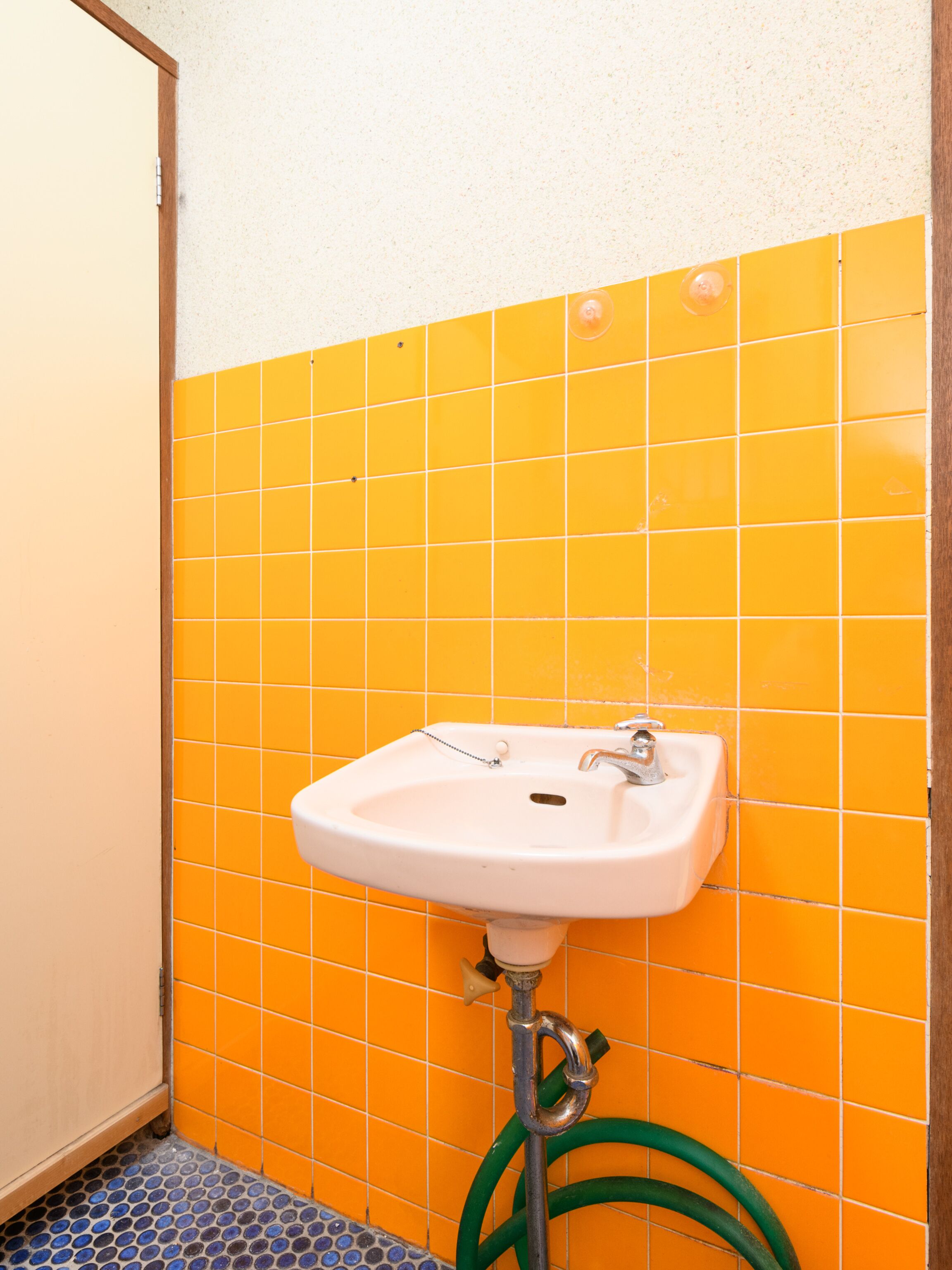 Un baño con un lavabo blanco, baldosas naranjas y un suelo con estampado azul y blanco.