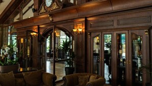 A lobby with a grand wooden staircase, a large clock, and a reception desk. - Maxi Park Hotel & Spa (Velingrad)
