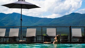 A pool area with lounge chairs and an umbrella, overlooking a mountainous landscape. - Maxi Park Hotel & Spa (Velingrad)