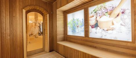 A wooden spa room with a bench, a wooden door, and a window with a view of flowers and a wooden mortar.