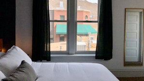 Une chambre d’hôtel avec un lit, une fenêtre avec des rideaux et une vue sur les bâtiments environnants.