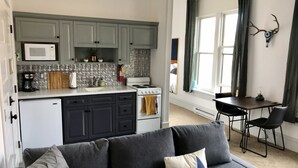 Une cuisine moderne avec des meubles gris, un four à micro-ondes et une cuisinière. On y trouve également un coin repas avec une table et des chaises.