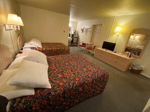 A hotel room with two beds, a desk, a chair, a television, and a mirror.