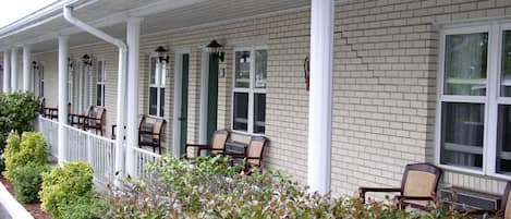 A building with a covered porch, white columns, and a brick facade.