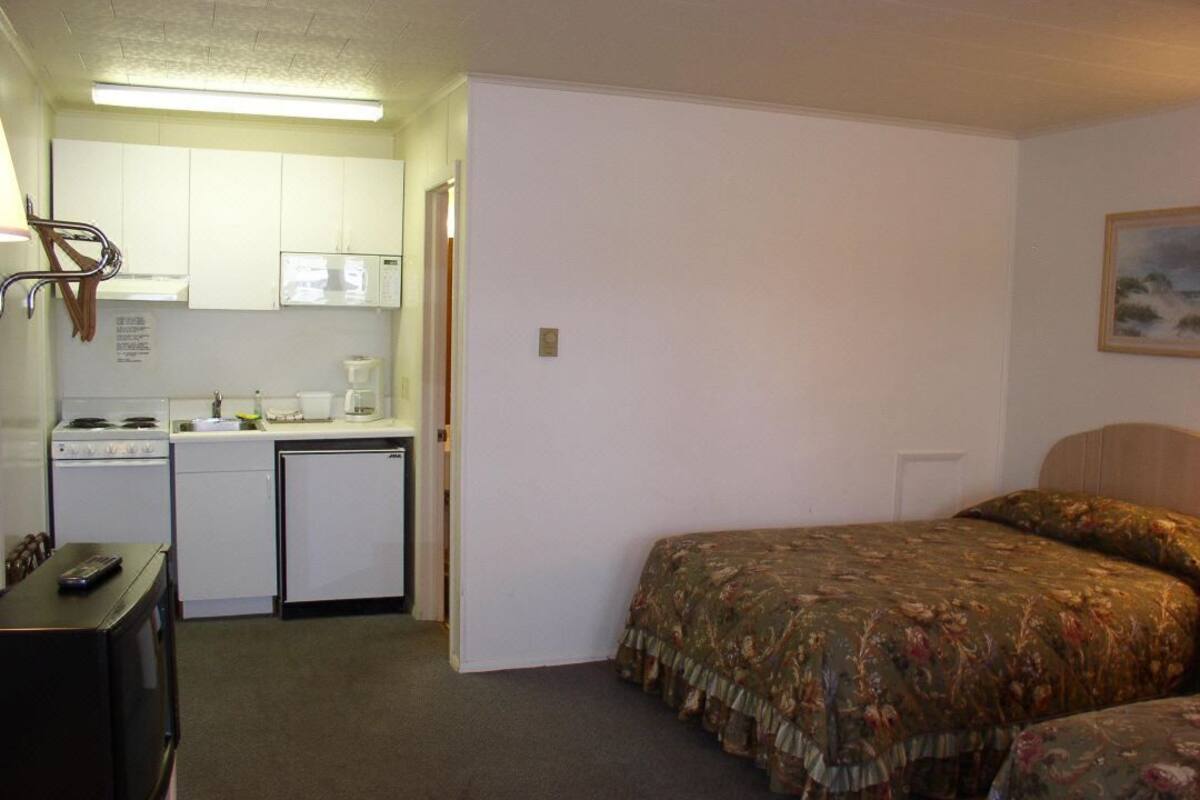 A compact room with a kitchenette, a bed, and a small television.