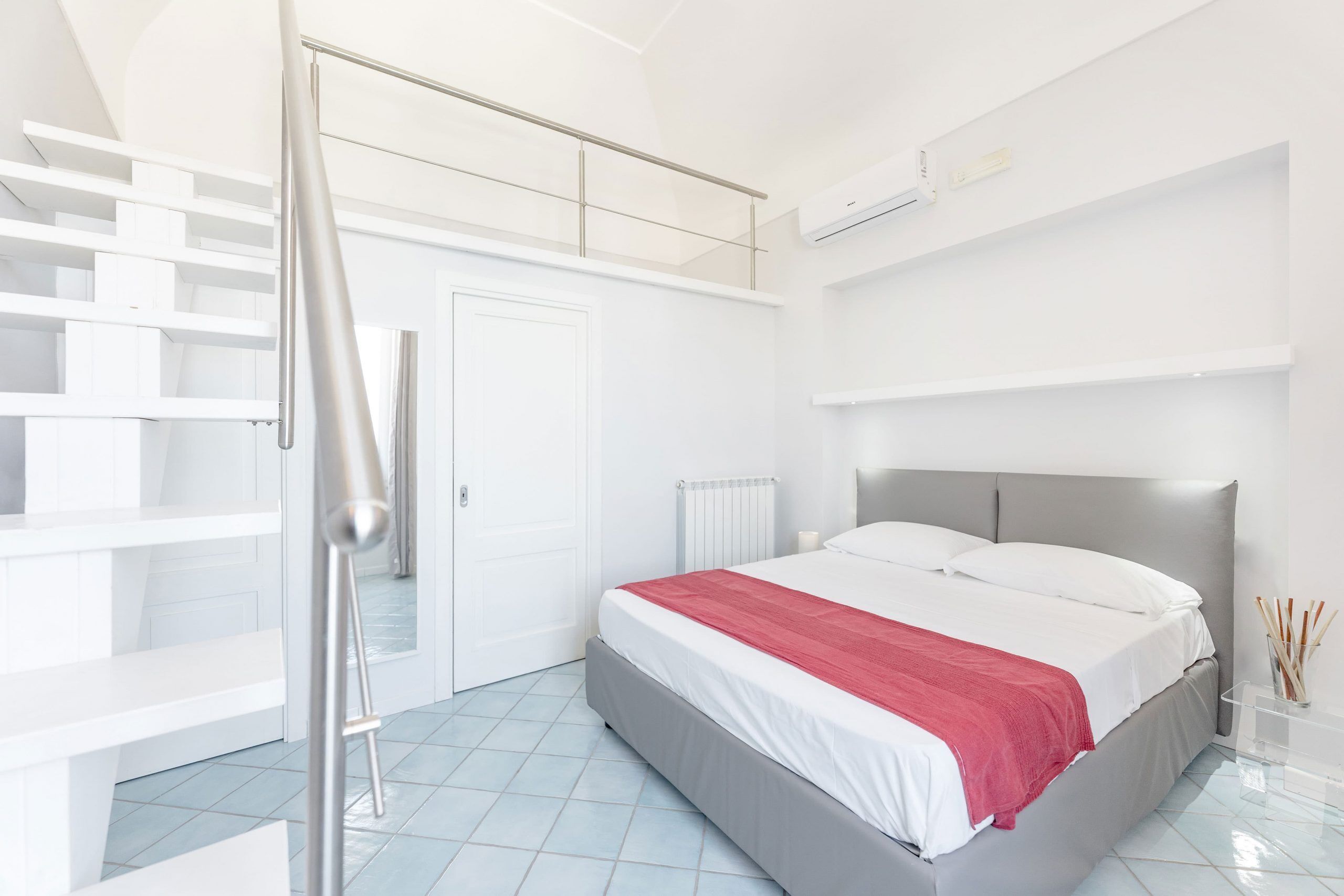 Un dormitorio moderno con una cama, un armario blanco y una escalera.