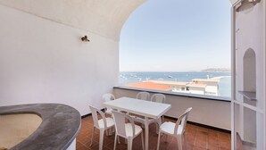 A balcony with a white table and chairs, a small sink, and a view of the sea and boats. - Fisherman's house in the harbor of Procida (Procida)