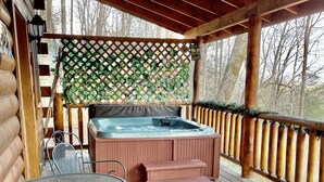 A wooden deck with a hot tub, metal chairs, and a table. - COZY CABIN!  Perfect Honeymoon or Private Getaway.  Hot tub & Fireplace (Sevierville)