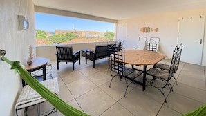 Ein Balkon mit Tisch, Stühlen, einer Hängematte und Blick auf Gebäude und Grünflächen.