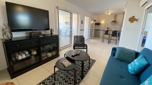 Ein modernes Wohnzimmer mit Flachbildfernseher, Sofa, Couchtisch und einem gemusterten Teppich.
