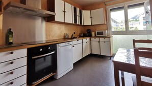 A compact kitchen with white cabinets, a black oven, and a microwave. - T4 apartment in the heart of Briançon, 400 m from the Serre-Chevalier slopes (Briançon)
