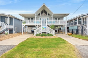 A two-story building with a central balcony, a covered entryway, and a small garden area. - Flip Flop Paradise - Unique 4 Bedroom Channel Home in Cherry Grove - Walk to Beach (North Myrtle Beach)