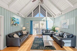 A spacious living room with two leather sofas, a coffee table, and a view through a glass door.
