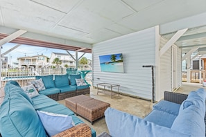 A covered outdoor seating area with a sofa, wicker furniture, and a table. - Flip Flop Paradise - Unique 4 Bedroom Channel Home in Cherry Grove - Walk to Beach (North Myrtle Beach)