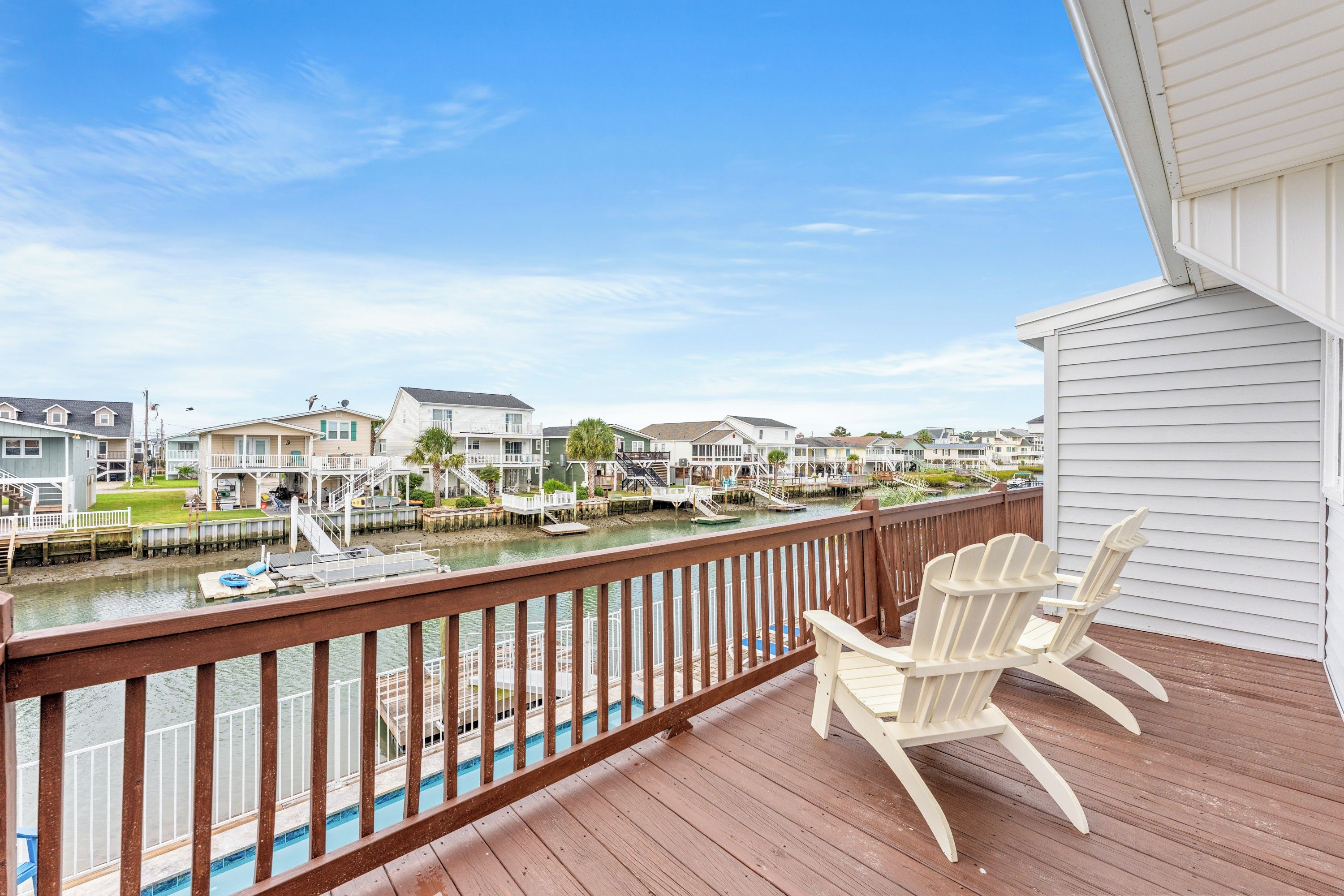 A wooden deck with a view of a marina and houses.