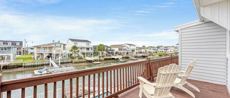 A wooden deck with a view of a marina and houses.