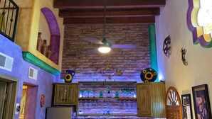 A rustic interior with exposed brick walls, wooden beams, and a ceiling fan. - Charming 1-Bedroom Loft in Old Port – Rooftop Views, BBQ Area & Steps to Malecon! (Puerto Peñasco)