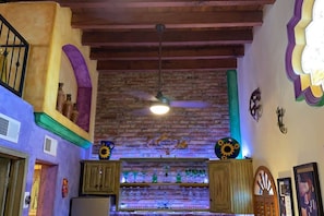 Exposed brick walls and wooden beams create a cozy atmosphere in this rustic retreat, featuring a ceiling fan and decorative elements.