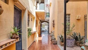 A narrow alleyway with tiled flooring, potted plants, and a gate leading to a building. - Charming 1-Bedroom Loft in Old Port – Rooftop Views, BBQ Area & Steps to Malecon! (Puerto Peñasco)