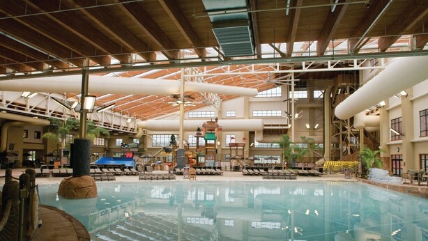 An indoor swimming pool with multiple lanes, lounge areas, and a covered seating area.