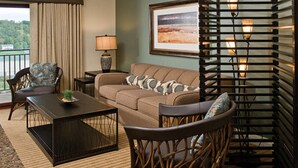 A living room with a sofa, armchairs, a coffee table, a lamp, and a framed picture on the wall.