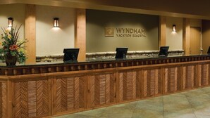 A reception desk at Wyndham Vacation Resorts with a stone counter and wooden paneling.