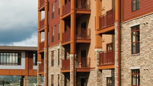 A multi-story hotel with balconies, stone facade, and a green lawn.