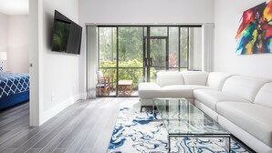 Un salon moderne avec un canapé blanc, une table basse en verre et un tapis à motifs bleus.