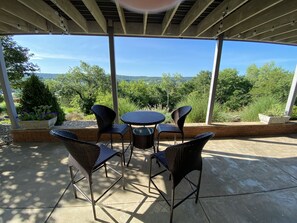 Une terrasse extérieure dotée d'une pergola, de meubles en osier et offrant une vue sur le paysage.