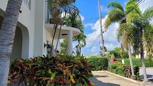 A white building with balconies, surrounded by palm trees and a clear blue sky. - Relaxing, Amazing beach, pool, Cheap cars, quiet area, surfers paradise 2 (Atlantic Shores)