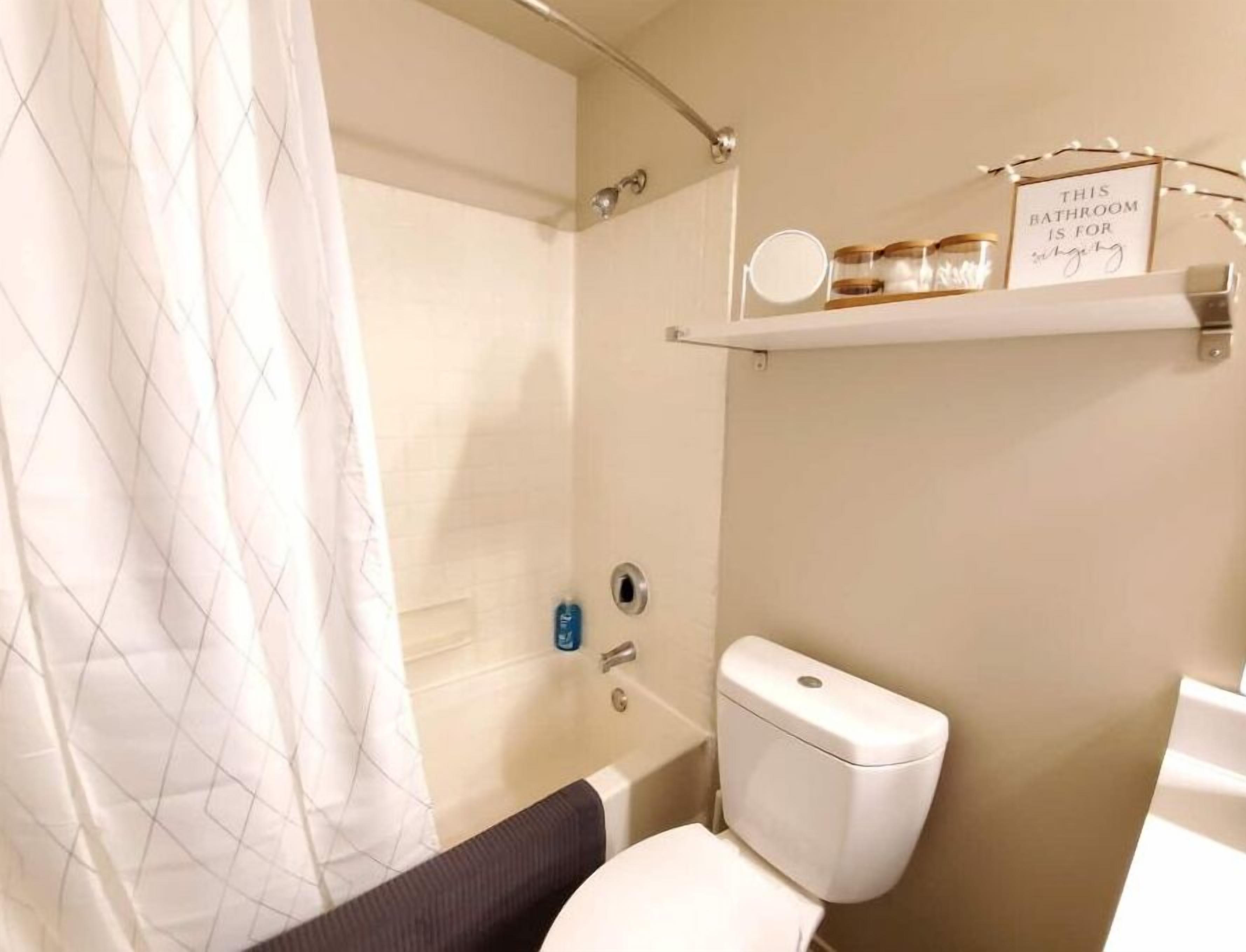 Un baño con ducha, inodoro y un estante con artículos de aseo.