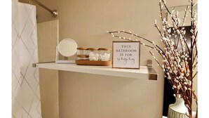 A bathroom vanity with a mirror, a framed sign, and decorative branches.