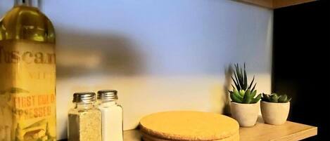 A shelf with a bottle, two jars, and three potted plants.