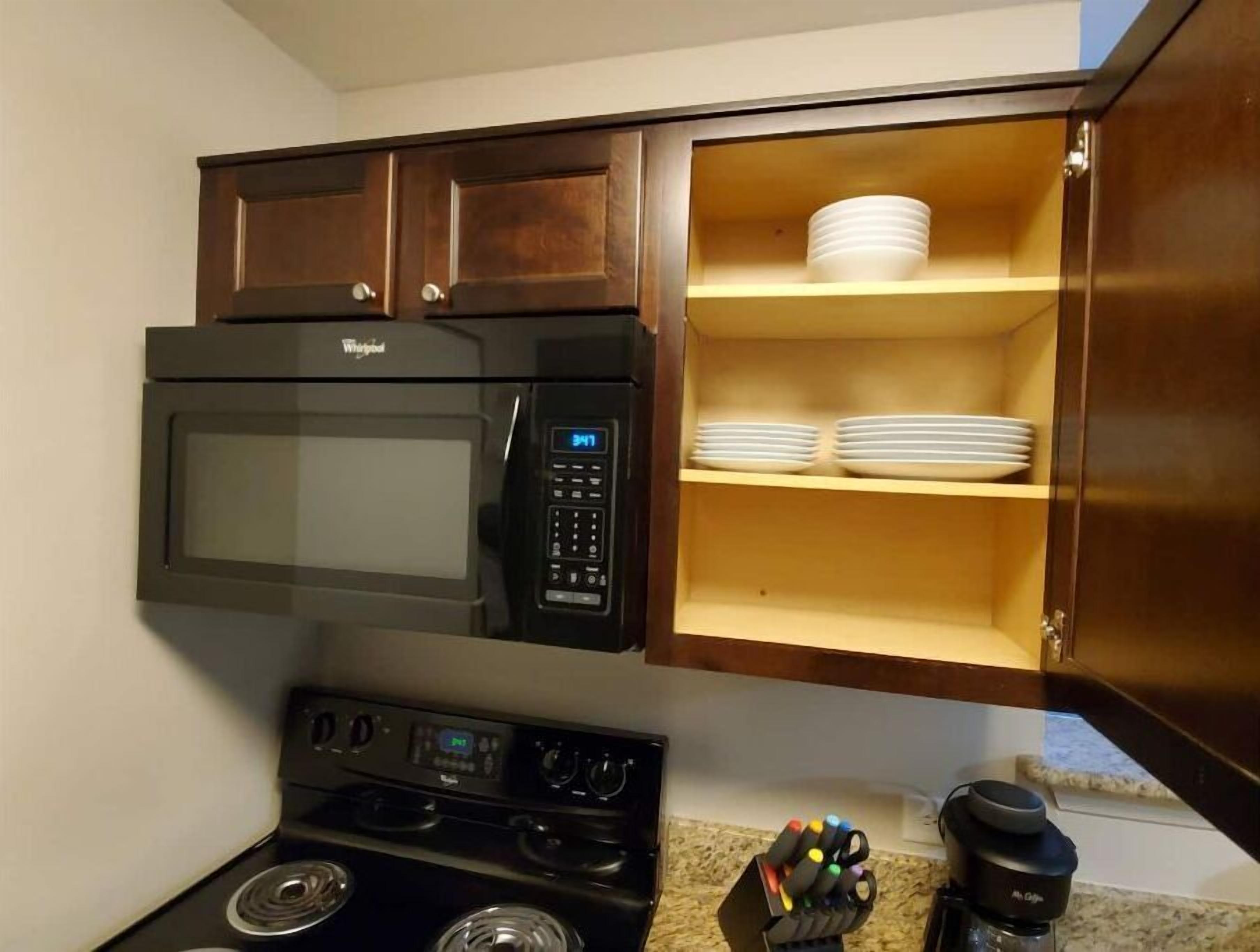Una cocina compacta con microondas, estufa y armarios de madera.