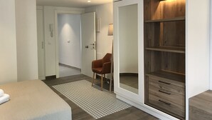 Un dormitorio moderno con un armario grande, una mesita de noche y una silla.