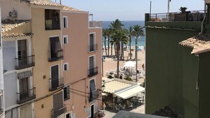 Una zona urbana costera con edificios de varios pisos, una playa con palmeras y un cielo despejado.