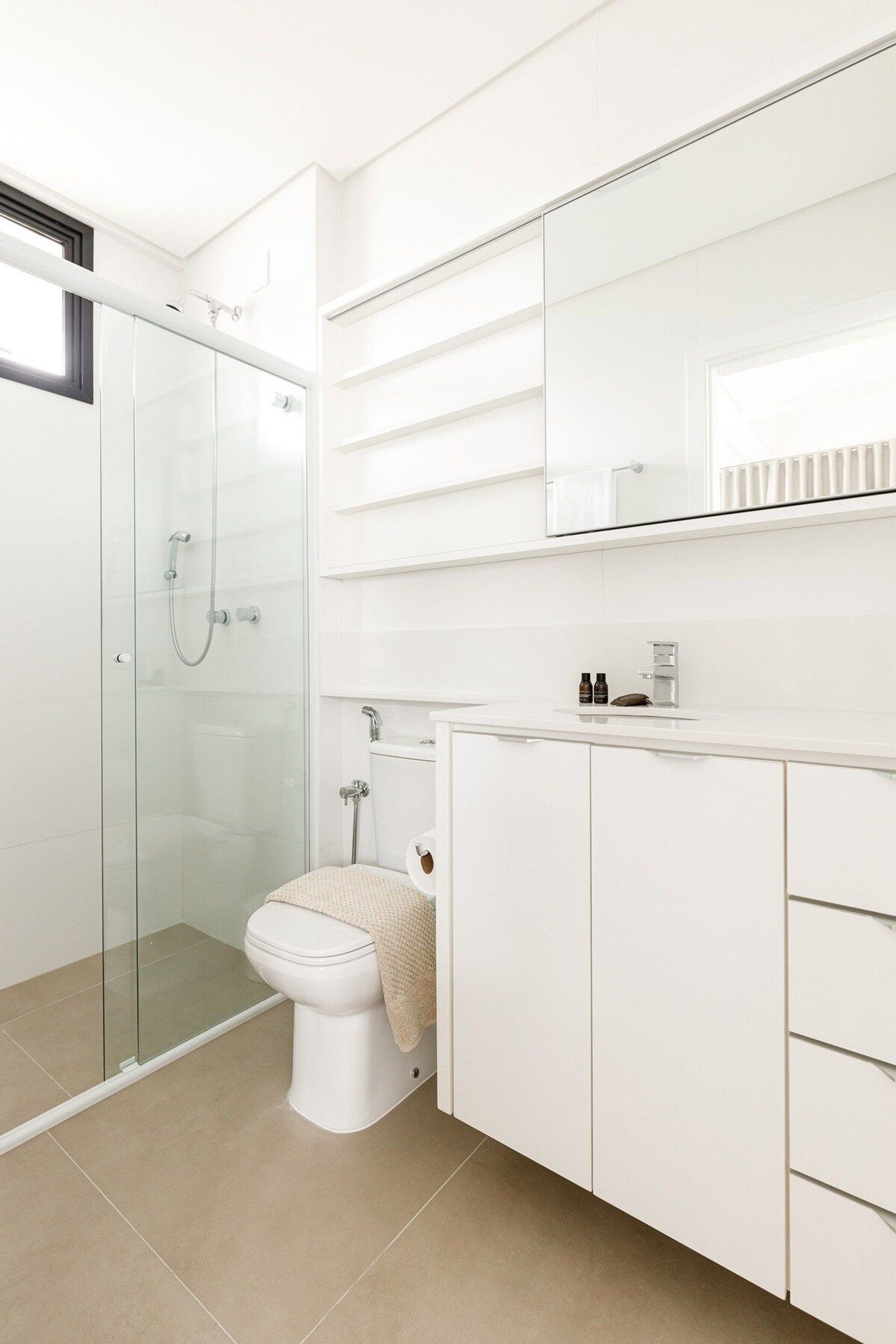 Un baño moderno con ducha de vidrio, inodoro y tocador con espejo.