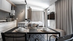 A modern hotel room with a dining area, kitchenette, and a bed with curtains. - ZEE Studios by Viva - Studios a 200m da beira-mar norte (Florianópolis)