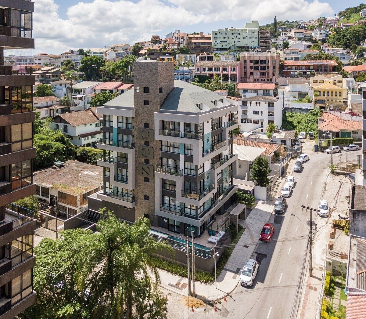 A multi-story building with balconies, a street in front, and surrounding residential buildings.